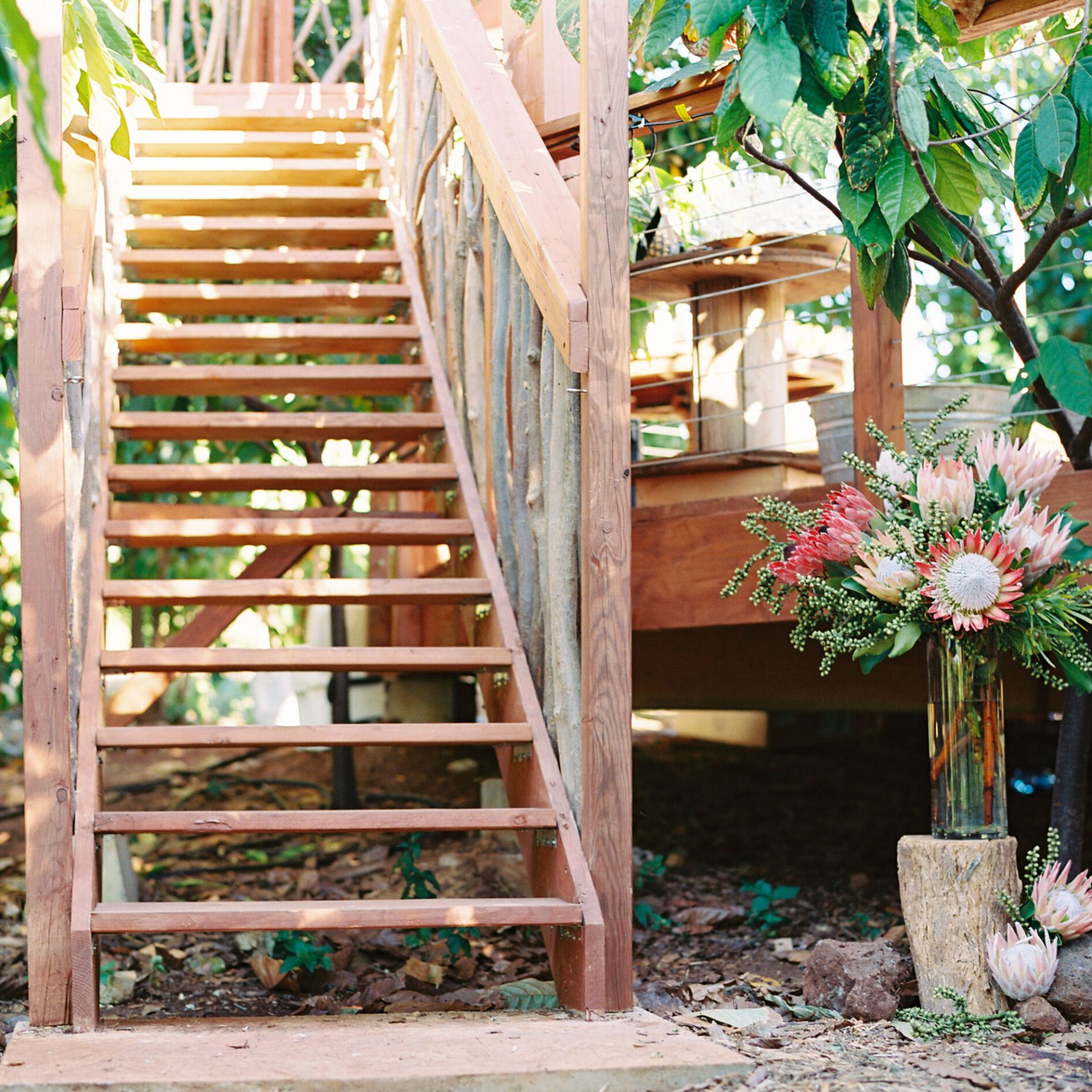 a vase of flowers sitting on top of a wooden fence